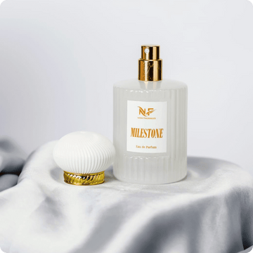 Perfume bottle with gold cap and 'Milestone' label on a white fabric background