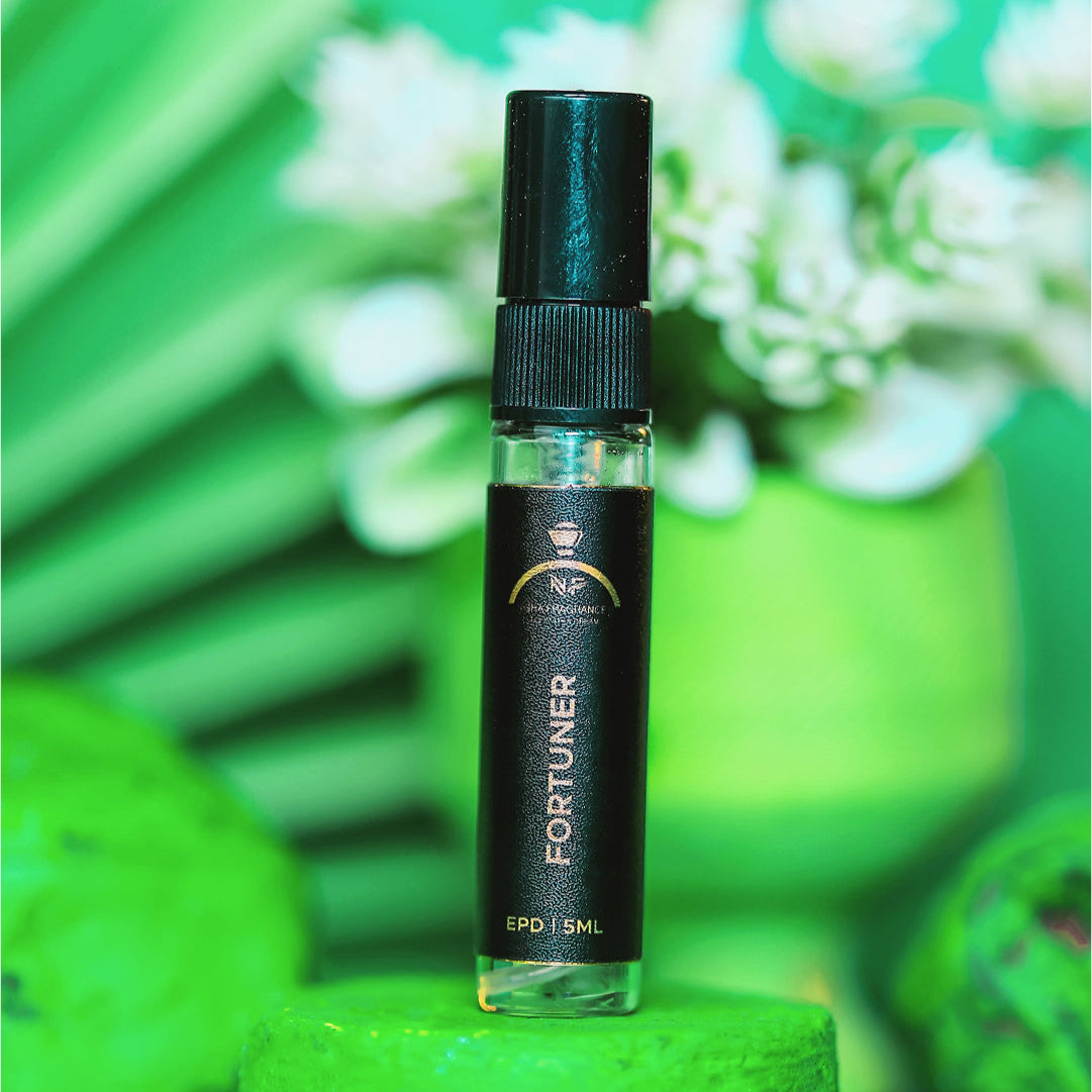 Small black bottle labeled 'Fortuner' on a green surface with a blurred green and white floral background