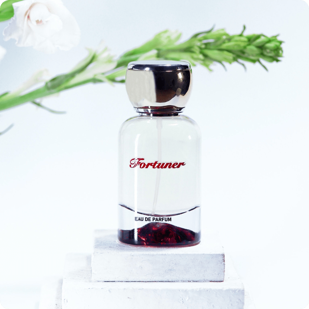 Perfume bottle labeled 'Fortuner' on a white background with greenery.