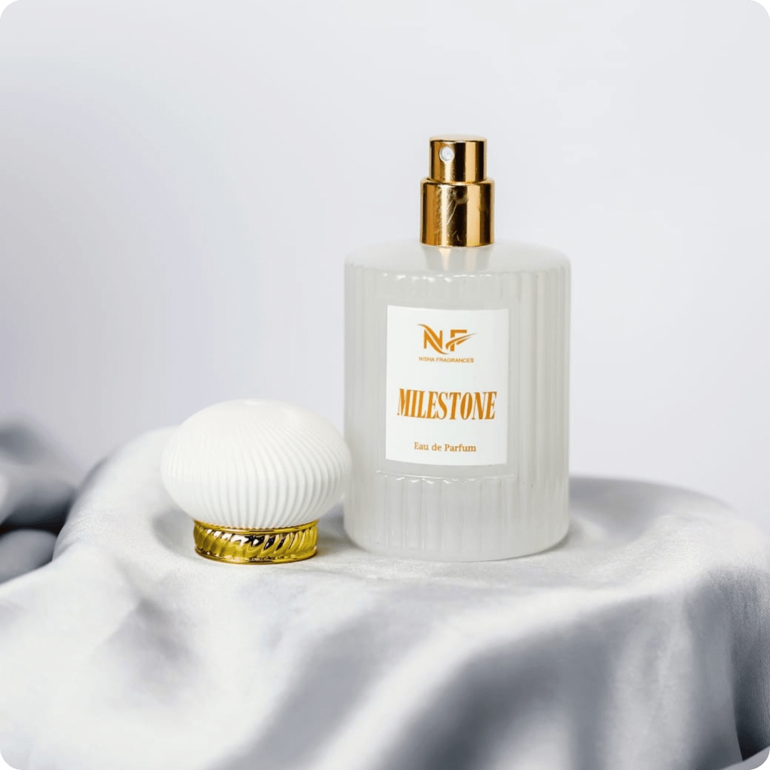 Perfume bottle with gold cap and 'Milestone' label on a white fabric background